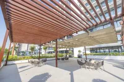 a pavilion with chairs and tables and a building at Bright Studio with Pool Access - Azizi Riviera in Dubai