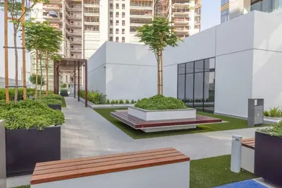 a courtyard with a bench and trees and buildings at Bright Studio with Pool Access - Azizi Riviera in Dubai