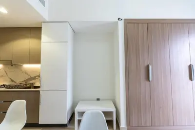 a kitchen with a table and a white cabinet at Peaceful and Cozy Studio, Burj Khalifa View in Dubai