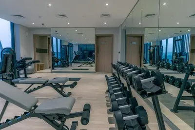 a gym with rows of exercise equipment and mirrors at Peaceful and Cozy Studio, Burj Khalifa View in Dubai