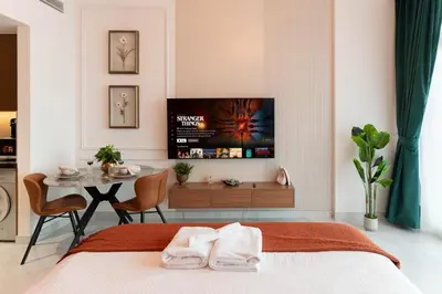 a bedroom with a bed and a table with a tv at Elegant Studio with Balcony & Pool in Dubai Studio City in Dubai