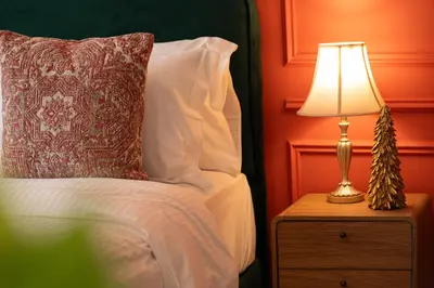 a bed with a pillow and a lamp on a night stand at Elegant Studio with Balcony & Pool in Dubai Studio City in Dubai