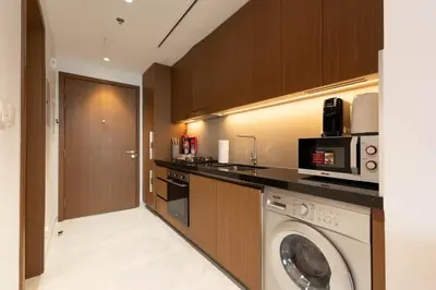 a kitchen with a washing machine and a microwave at Elegant Studio with Balcony & Pool in Dubai Studio City in Dubai
