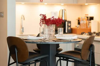 a table with chairs and a vase with flowers on it at Luxury 1BR Retreat near DIFC & Downtown Dubai in Dubai
