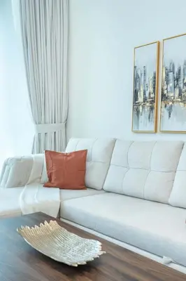 a living room with a white couch with orange pillows at PVH - Pristine 1BR Minutes to Circle Mall - Binghatti Amber in Dubai
