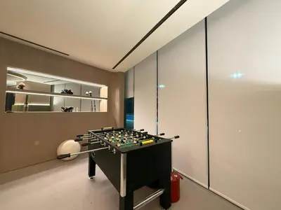 a room with a foosball table in front of a wall at Modern 1BR Apartment with Private Pool in JVC in Dubai