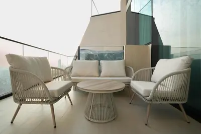 a balcony with chairs and a table and a couch at Elegant Apartment with Balcony Pool & Parking in Dubai
