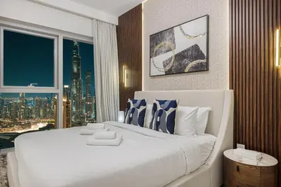 a large white bed in a room with a window at Stylish 4BR with Burj & Fountain View, Dubai Mall Connection in Dubai