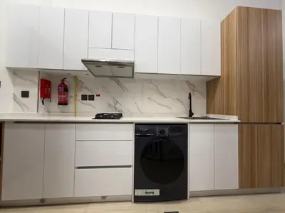 a kitchen with white cabinets and a black dishwasher at Chic Studio Living Elysee III by Pantheon in Dubai