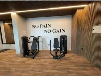 a gym with dumbbells and a sign saying no pain no gain at Chic Studio Living Elysee III by Pantheon in Dubai