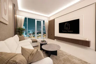 a living room with a white couch and a tv at Canal Stays in Dubai