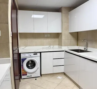 a kitchen with white cabinets and a washing machine at Miraclema Stays Al Barsha 1 in Dubai