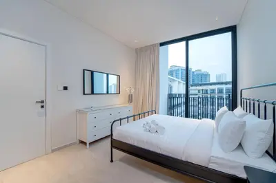 a bedroom with a white bed and a balcony at Sleek New 1 Bed with Padel Court in Arjan in Dubai