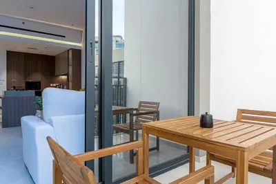a table and chairs on a balcony with a couch at Sleek New 1 Bed with Padel Court in Arjan in Dubai