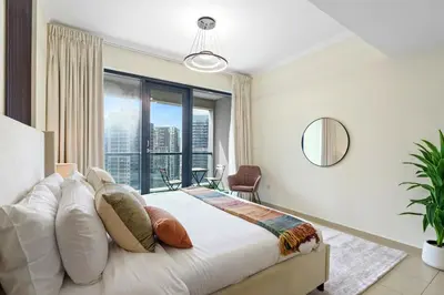 a bedroom with a large bed with a large window at HAVN - High Floor 1 bedroom in JLT in Dubai