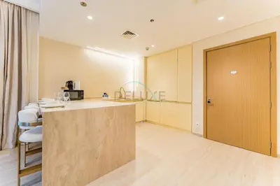 a kitchen with a counter and chairs in a room at Elegant 1BR, Easy Access to Creek Harbour Night Vision - Summer at Creek Beach Building 3 by Deluxe Holiday Homes in Dubai