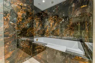 a bathroom with a marble wall with a white sink at Elegant 1BR, Easy Access to Creek Harbour Night Vision - Summer at Creek Beach Building 3 by Deluxe Holiday Homes in Dubai