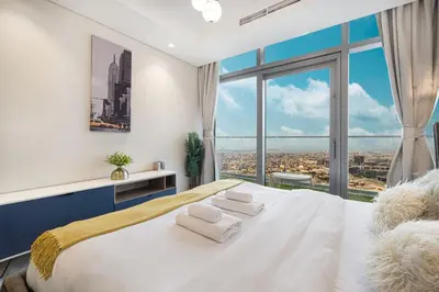 a bedroom with a white bed with a large window at Famous Sky Pool at Paramount's King's 2BR in Dubai