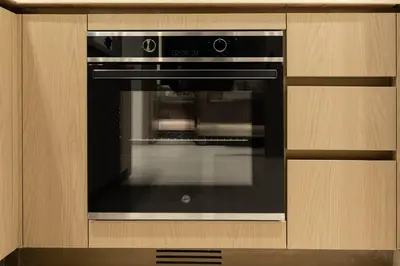 a black oven in a kitchen with a wooden cabinet at Luxury Skyline Apartment with Pool in Dubai