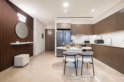 a kitchen with two stools and a table and a refrigerator at Burj Khalifa Front Ultra Luxe Designer Residence in Dubai