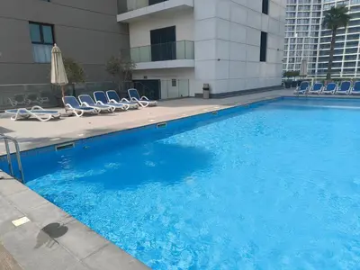a large blue swimming pool with chairs and a building at High-Floor Luxe 1BR - Burj Khalifa View - Business Bay in Dubai
