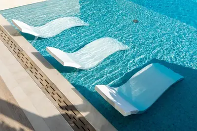 a swimming pool with two white chairs in the water at Refined Apartment with Private Balcony Pool in Dubai