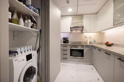 a white kitchen with a washing machine in it at Spacious 1BR & Study Burj Khalifa View, Downtown in Dubai