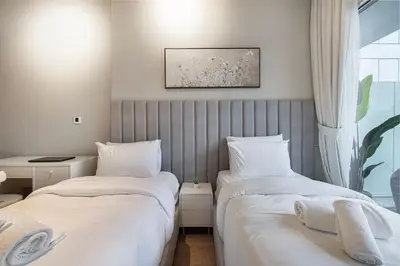 two beds in a room with white sheets and a window at Designer 2BR with Burj View 5 Min to Dubai Mall in Dubai