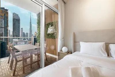 a bedroom with a bed and a balcony with a table at Designer 2BR with Burj View 5 Min to Dubai Mall in Dubai