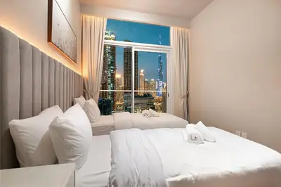 a bedroom with two white beds and a window at Designer 2BR with Burj View 5 Min to Dubai Mall in Dubai