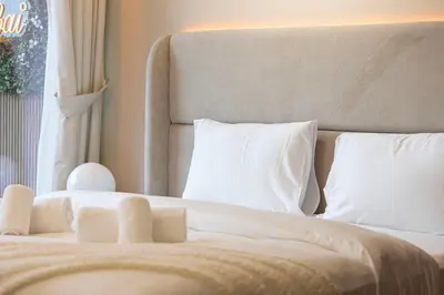 a bed with white sheets and pillows in a room at Designer 2BR with Burj View 5 Min to Dubai Mall in Dubai