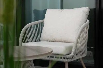 a wicker chair with a pillow on it next to a table at Luxury City Apartment with Private Pool in Dubai