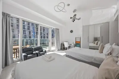 a large white room with two beds and a chair at Elite Escapes - Glamorous Damac Heights - 2 BR in Dubai