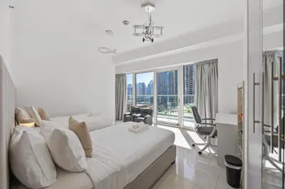 a white bedroom with a large bed and a desk at Elite Escapes - Glamorous Damac Heights - 2 BR in Dubai