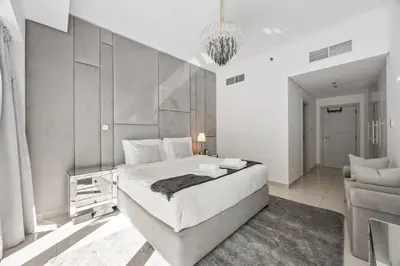 a white bedroom with a large bed and a couch at Elite Escapes - Glamorous Damac Heights - 2 BR in Dubai