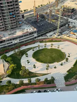 an aerial view of a park in front of a building at Opalz 1 bhk luxury apt for family and couple with swimming pool in Dubai