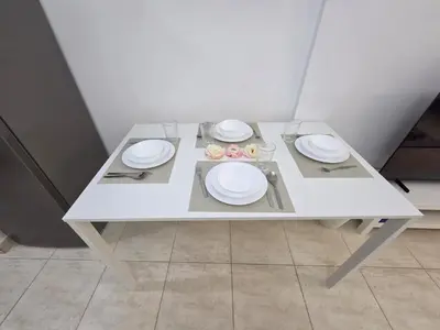 a white table with plates and bowls on it at Skycourts - Well furnished Studio apartment in Dubai