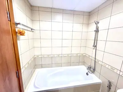 a white tiled bathroom with a bath tub at Skycourts - Well furnished Studio apartment in Dubai