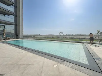 a man standing next to a swimming pool in a building at Modern Chic 1BHK Nobles Tower by Czechin in Dubai