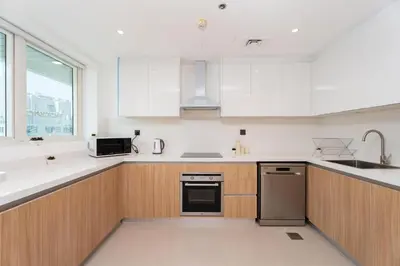 a kitchen with white counters and wooden cabinets at Gala Guests - Classic Opal Tower Suites Dubai Marina in Dubai