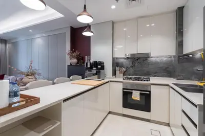 a kitchen with white cabinets and a stove top oven at Stylish 1BHK Retreat at Nobles Tower, by Czechin in Dubai
