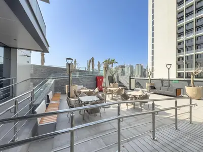 a balcony with chairs and tables on a building at Stylish 1BHK Retreat at Nobles Tower, by Czechin in Dubai