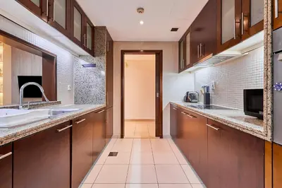 a large kitchen with wooden cabinets and a sink at Greenview 2BHK Stay in Dubai