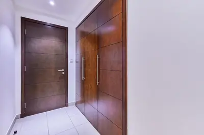 a hallway with wooden doors and a tile floor at Greenview 2BHK Stay in Dubai