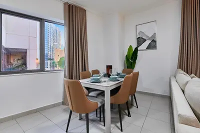 a dining room with a table and chairs and a couch at Greenview 2BHK Stay in Dubai