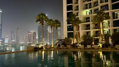 a hotel swimming pool with palm trees and a city at Stunning Canal View Studio Business Bay in Dubai