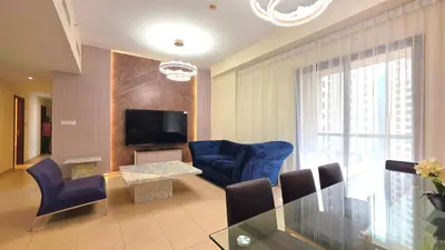 a living room with a glass table and blue chairs at Elan Rimal Bahar Suites, 1min walk to the Sea! Prime location JBR Beach Front in Dubai