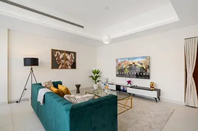 a living room with a blue couch and a tv at Luxury 3BR in Mada Residences - Walk to Dubai Mall in Dubai