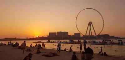 a group of people on a beach with a ferris wheel at Festive Winter Stay in JBR - Beach, Marina, Metro in Dubai