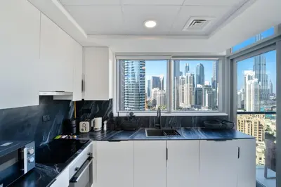 a kitchen with white cabinets and a view of the city at Marcopolo - Signature High-Floor Apartment Facing Burj Khalifa in Sabkhah